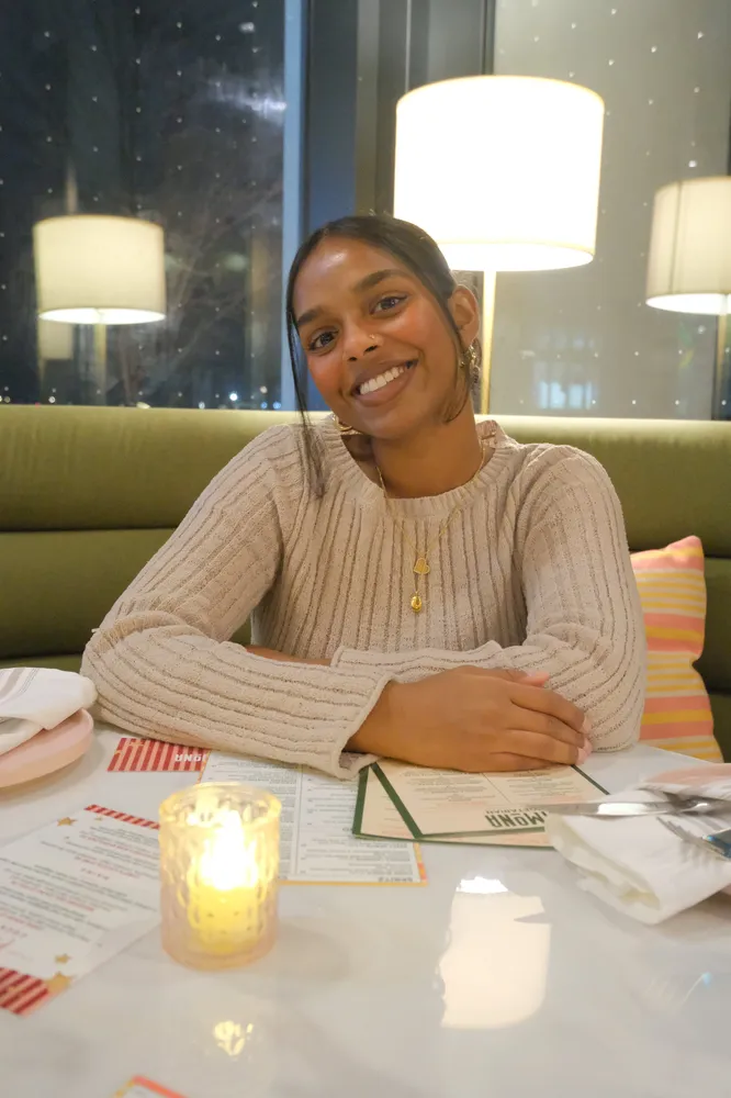A woman smiling across a candlelit restaurant table
