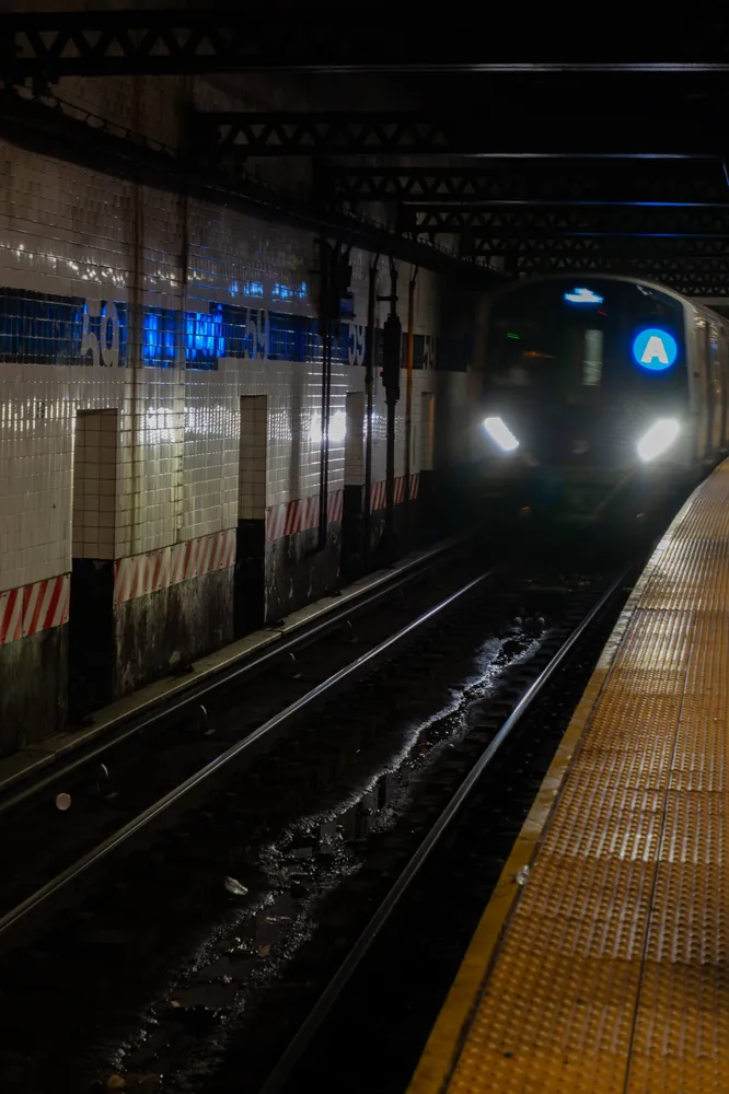 A subway train arriving beside a yellow platform edge